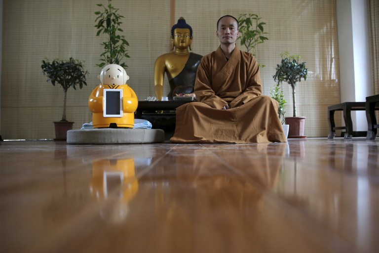 Master Xianfan sits next to robot Xian'er as he poses for photograph at Longquan Buddhist temple on the outskirts of Beijing, April 20, 2016.  REUTERS/Kim Kyung-Hoon