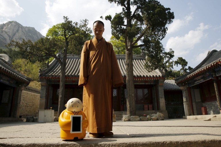 Master Xianfan looks at robot monk Xian'er as he prepares to pose for photograph in the main building of Longquan Buddhist temple on the outskirts of Beijing, April 20, 2016.  REUTERS/Kim Kyung-Hoon